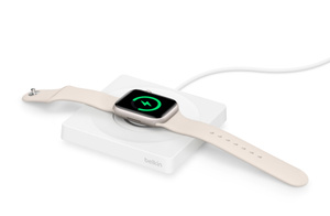 一块白色 Apple Watch 平放在白色充电器上充电。