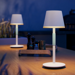 Two Philips Hue Go Portable Table Lamps on a dining table, illuminating its surface.