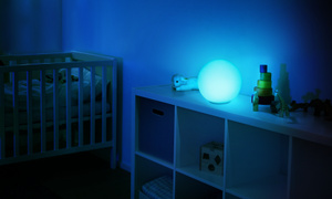 Lampada LED Eve Flare, illuminata di blu, posizionata su uno scaffale nella cameretta di un neonato.