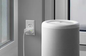 The Eve Energy plug, inserted into a standard power socket with green LED power indicator ON, connected to a lamp.