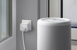 The Eve Energy plug, inserted into a standard power socket controlling a room humidifier.