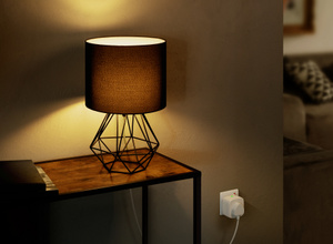 The Eve Energy plug, inserted into a standard power socket connected to a lamp.