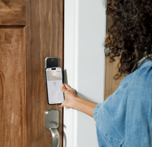 Person holding iPhone close to the installed Yale Assure Lock 2 Plus to both lock and unlock the door.