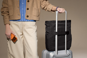 Aer Go Tote 2 bag secured to a carry-on bag via the luggage handle pass-through on back