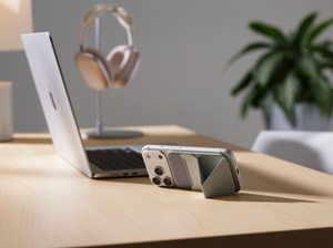 Moft MagSafe Wallet-standaard, achterkant, iPhone bevestigd aan Moft Wallet-standaard, beide in liggende oriëntatie, geplaatst op bureau naast een MacBook