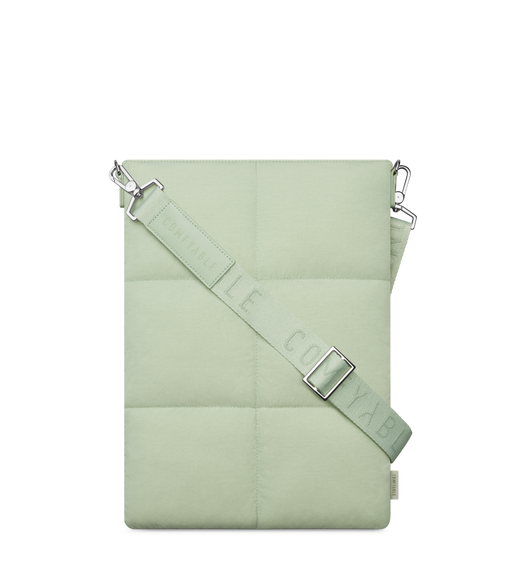 Comfyable Puffer MacBook Tote, side exterior, sage green color, six-panel stitched design, cross body strap at front connected to tote via clips, logo tag at lower right, text reads: Comfyable