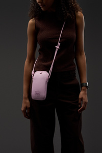 Herschel Cloudform Crossbody Bag for iPhone, pink colour, adjustable twill webbing strap slung around a person’s neck and over their shoulder