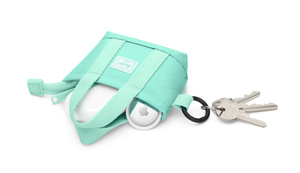 Herschel AirPods Tote Charm, top exterior, mint green fabric colour, open, with AirPods case and AirTag tucked half‑way in, mint green zip pull on left, black metal keyring with keys attached