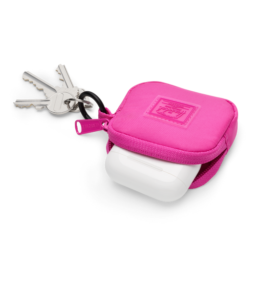 Herschel Cloudform AirPods Charm, top exterior, pink fabric color, open, with AirPods case tucked half-way in, pink zipper pull at left, black metal keyring with attached keys