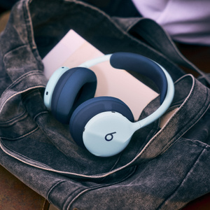 네이비 색상 헤드밴드 쿠션과 이어컵 쿠션이 장착된 스카이 색상 Beats 360이 열린 데님 가방 안에 놓여 있는 모습