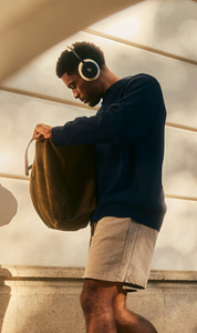 شخص يرتدي سماعات الرأس Beats 360 بلون أسود مع بطانة Performance Knit بلون أبيض الغيوم.