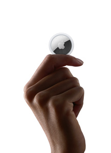 AirTag held between thumb and index finger, white color, Apple logo centered