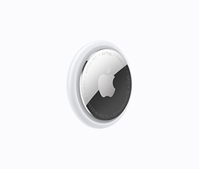 AirTag, 3/4 angle, circular shape, white color ring around outer edge, front exterior, reflective silver color material, Apple logo centered, etching around inner edge reads: AirTag - FIND MY - NFC - BLUETOOTH LE - ULTRA WIDEBAND - IP67 - APPLE INC.