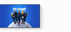 Apple&nbsp;TV promo displayed on Apple&nbsp;TV&nbsp;4k, title: Ted Lasso, Jason Sudeikis smiling broadly, Juno Temple smiling with her hand on her hip, Brett Goldstein in a leather jacket, Hannah Waddingham with fist raised, Brendan Hunt holding a clipboard, cast fanned out on an oversized football, blue gradient background.