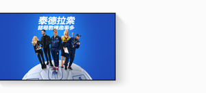 在 Apple TV 4K 上顯示的 Apple TV 宣傳畫面，片名為泰德拉索：錯棚教練趣事多；畫面中的 Jason Sudeikis 笑容燦爛，Juno Temple 面帶笑容、單手叉腰，Brett Goldstein 身穿皮外套，Hannah Waddingham 高舉拳頭，Brendan Hunt 手持寫字板；演員們在巨型足球上呈扇形排列，背景為藍色漸層。
