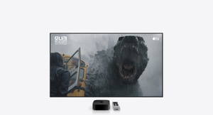 블랙 색상 Apple TV 4K와 실버 색상 Apple TV Remote를 대형 TV 디스플레이 아래 놓아둔 모습