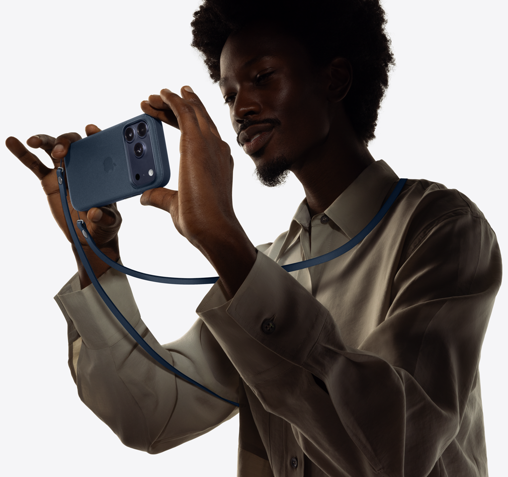 Людина робить фотографію, одягнувши ремінець CrossBody, прикріплений до iPhone 17 Pro в силіконовому чохлі.
