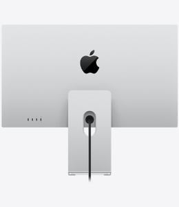 Studio Display XDR, back exterior, silver color, stand mounted at bottom below centered black glossy Apple logo, two Thunderbolt 5 ports and two USB-C ports on lower-left side, power port centered at bottom with cable cutout in stand, display connected to angled tilt- and height-adjustable arm on vertical stand, power cord attached