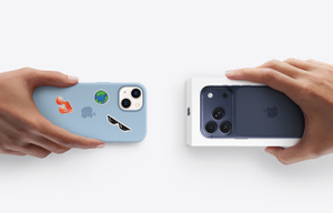 A hand holding an old iPhone in a case with stickers and another hand holding a new iPhone in its box