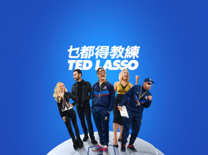 Apple TV+ promo, title: Ted Lasso, Jason Sudeikis smiling broadly, Juno Temple smiling with her hand on her hip, Brett Goldstein in a leather jacket, Hannah Waddingham with fist raised, Brendan Hunt holding a clipboard, cast fanned out on an oversized soccer ball, blue gradient background.