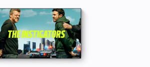 Title, The Instigators, promo for new Apple Originals every month on Apple TV+, Matt Damon and Casey Affleck, dressed casually, getting handcuffed with a skyline in the background.