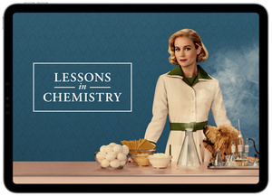 Title, Lessons in Chemistry, Brie Larson stands in front of a counter, on her right are ingredients for cooking, including eggs, pasta, and cheese, on her left are tools for chemistry experiments, including beakers, vials, and flasks, her dog looks up at her expectantly, its head peaking just above the counter.