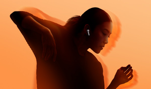 Person dancing, bright orange background, wearing white AirPods 4